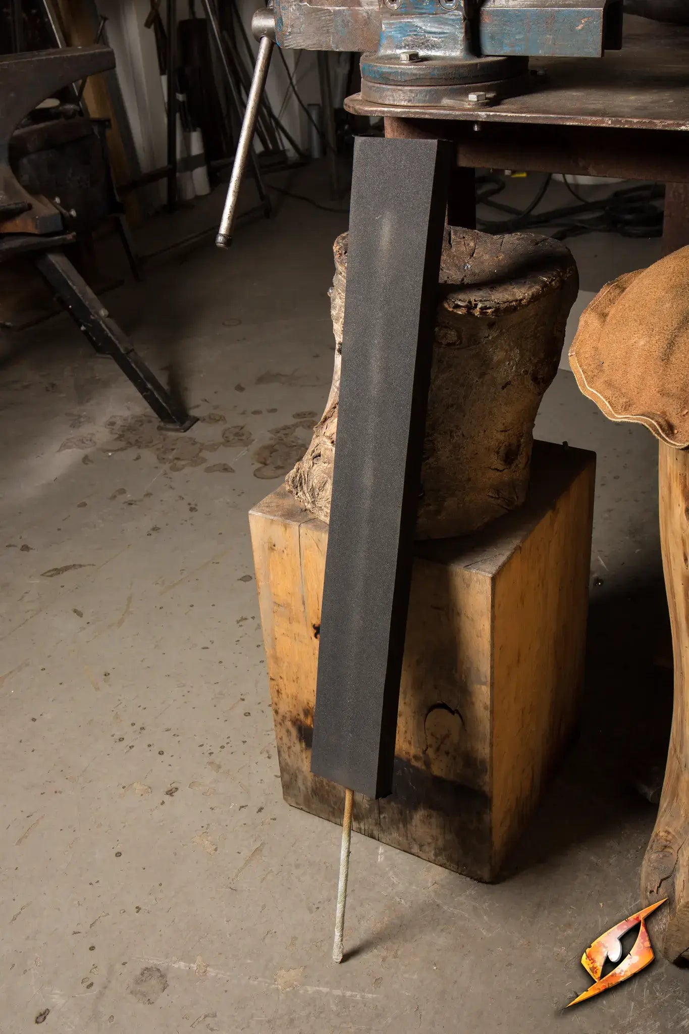 DIY Weaponry black foam blade resting on a workbench in a workshop.
