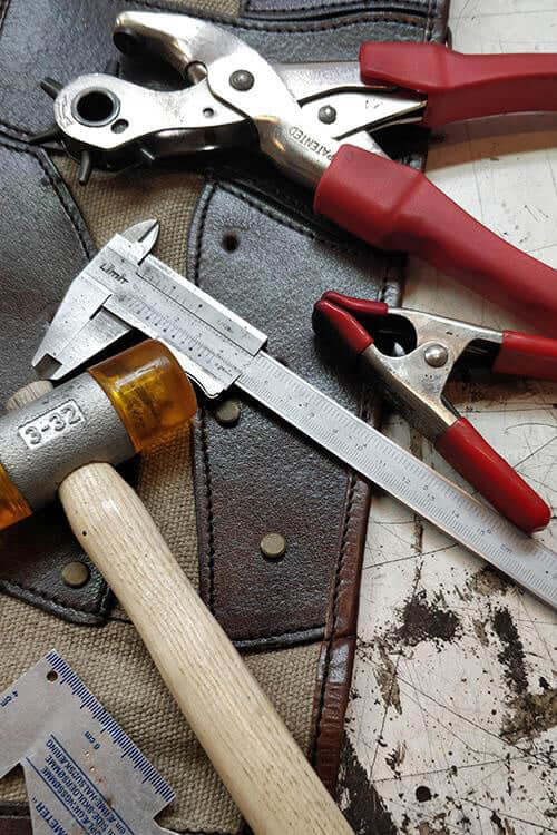 Various tools including pliers, calipers, and a hammer on a leather surface for Services.