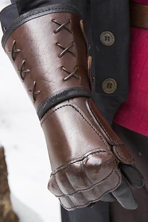 Close-up of a brown leather glove showcasing intricate stitching, emphasizing the quality of the leather.