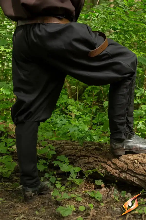 Medieval Pants on a person standing on a log in a lush green forest setting.