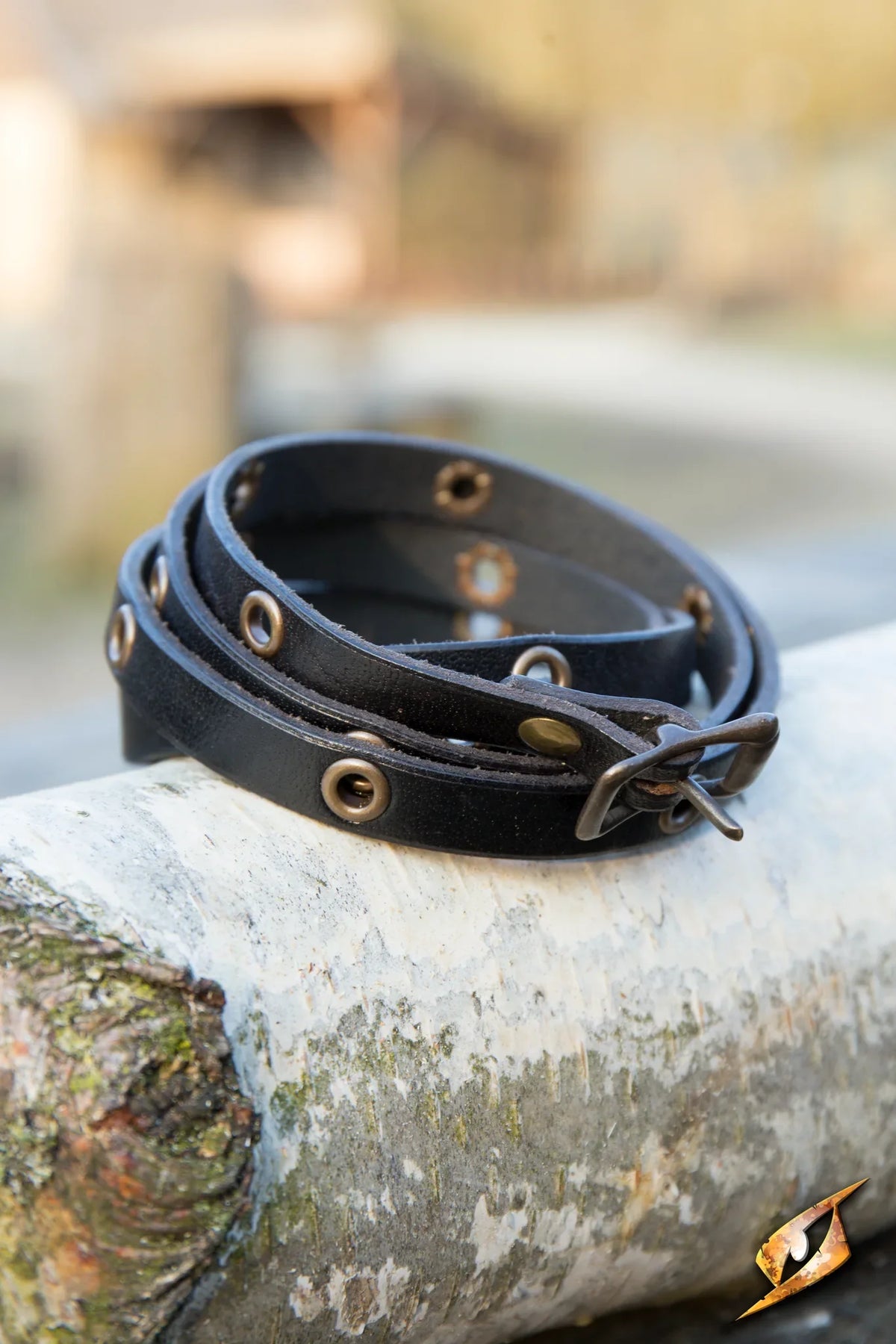 Multistrap Bracelet displayed on a log, showcasing its unique design with decorative features and sturdy material.