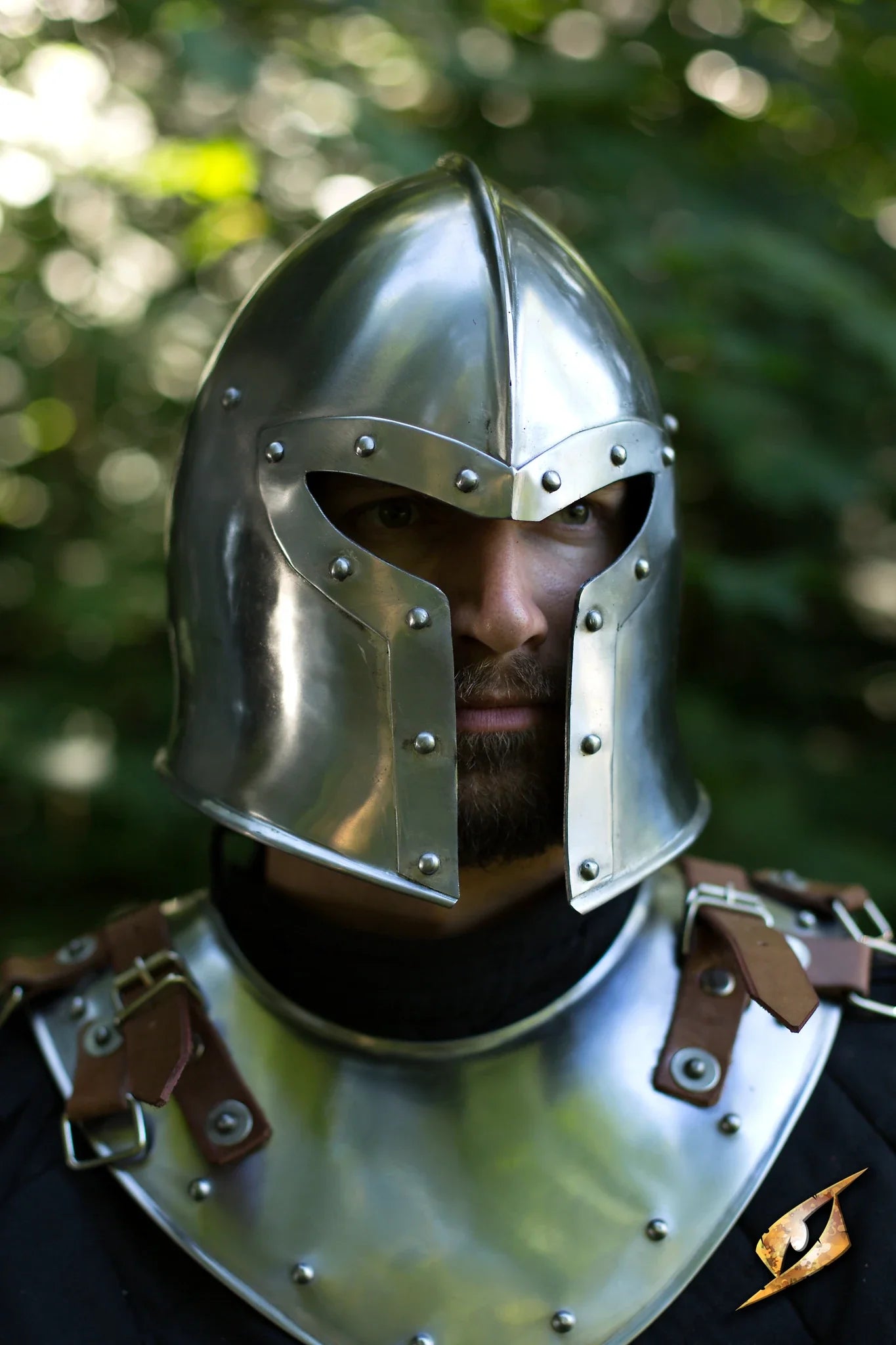 Close-up of a soldier wearing a shiny Barbuta helmet with detailed straps and armor.