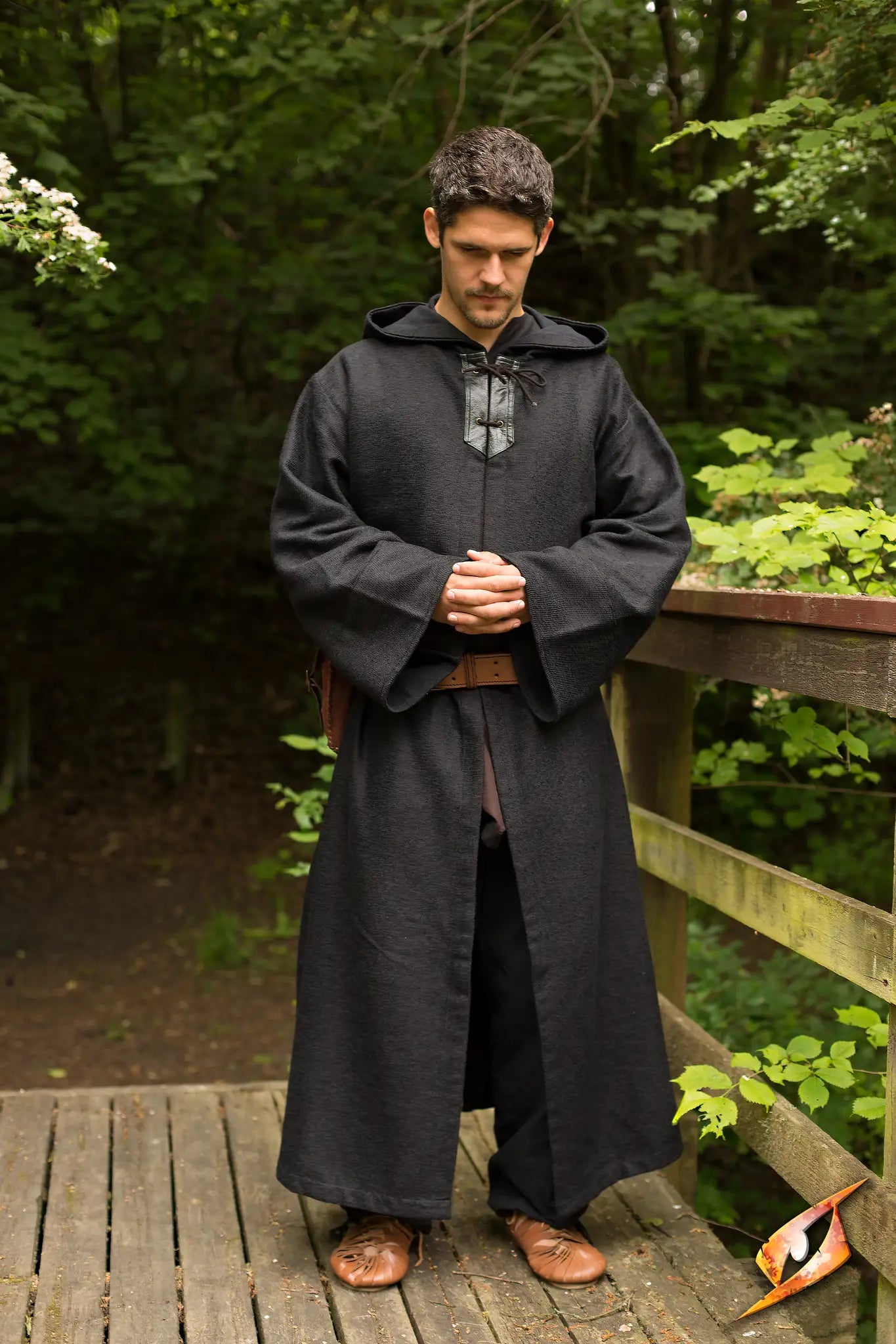 Robe Benedict worn by a man standing on a wooden bridge surrounded by greenery, evoking a mystical atmosphere.