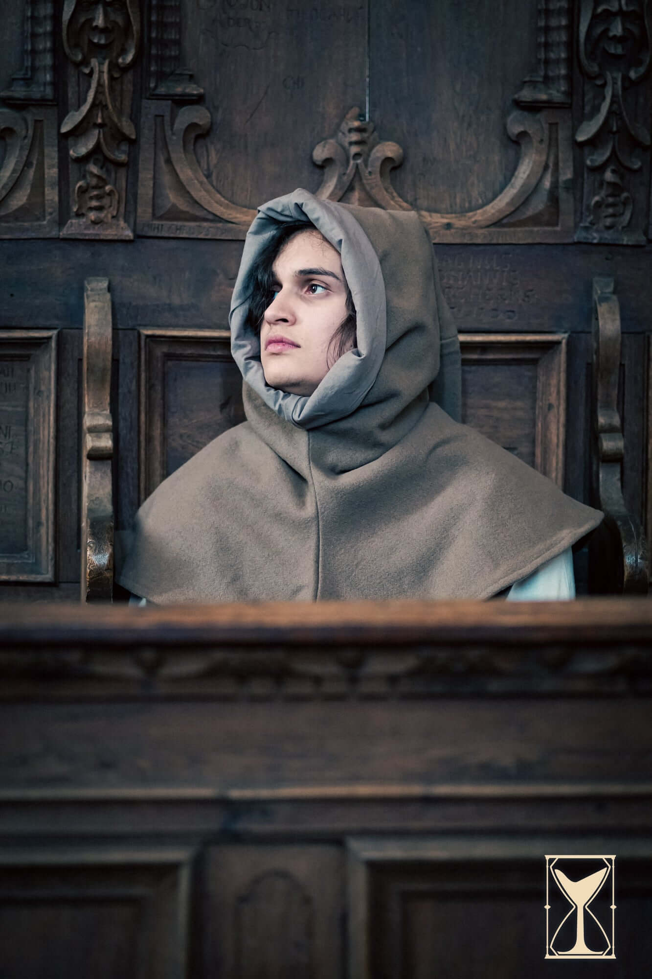 Simple Liripipe Hood - Brushed Wool worn by a person sitting in a medieval setting.