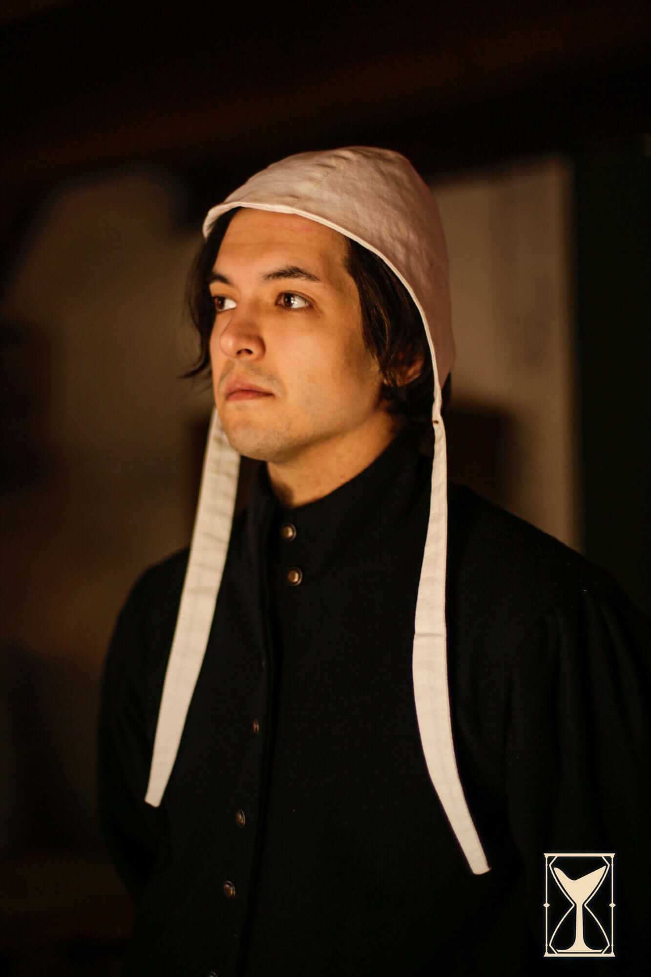 Close-up of a man wearing a Coif 12th century, featuring a simple design and fabric ties.