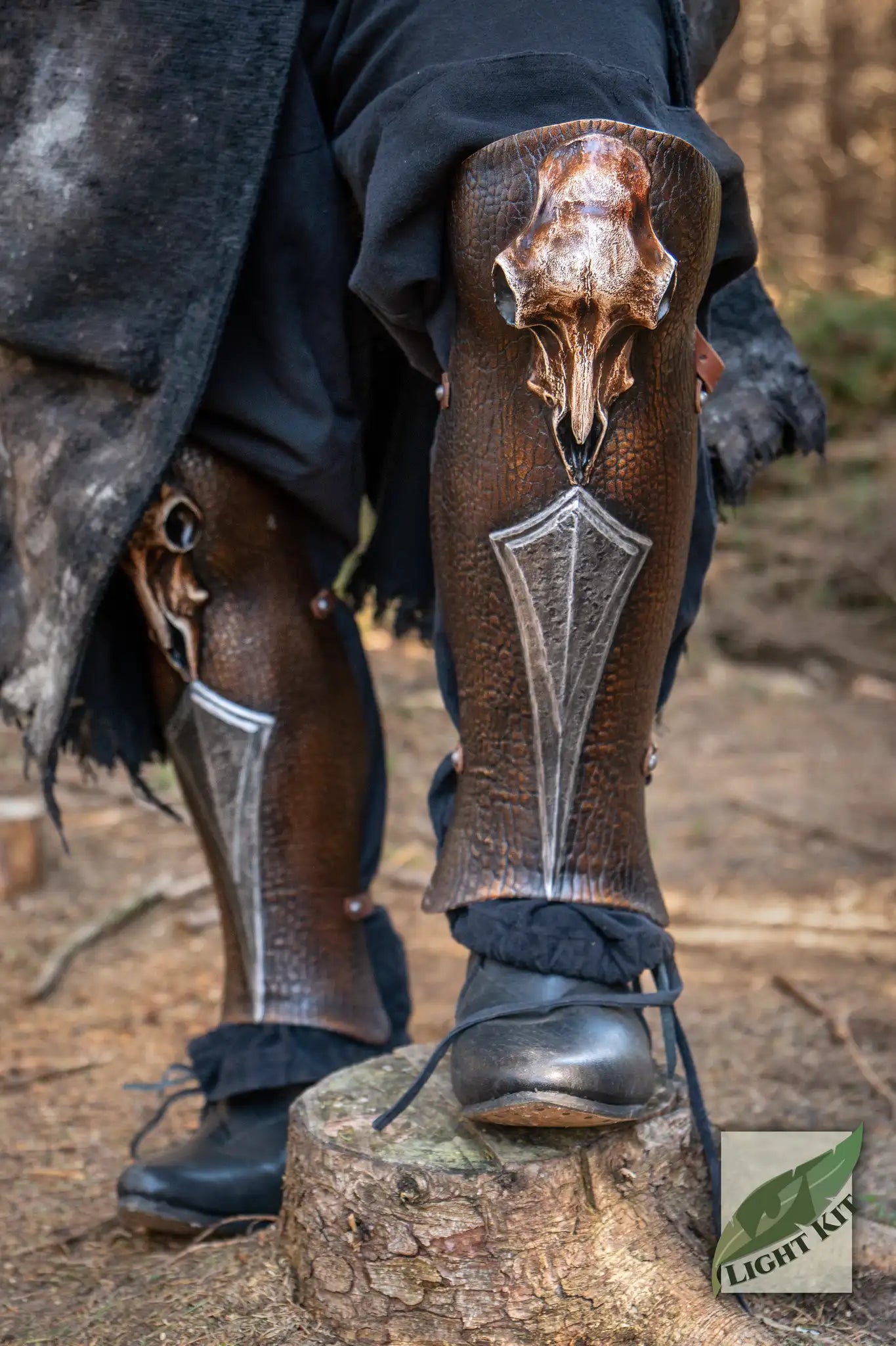 Barbarian Greaves PU - L/XL displayed on legs with skull embellishment in a forest setting.
