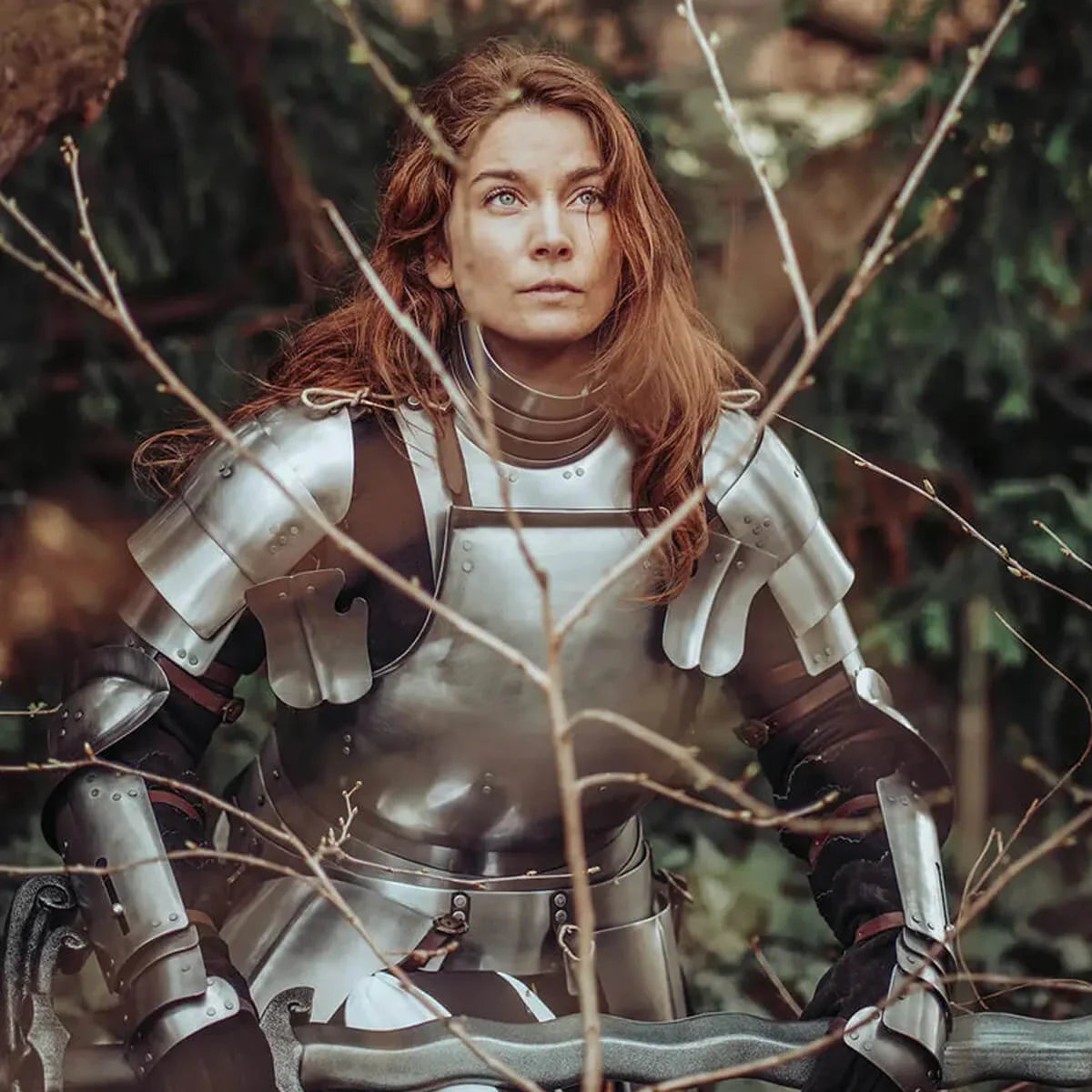 Woman in shining armor gazes thoughtfully while surrounded by branches in the scene titled Knight Time.