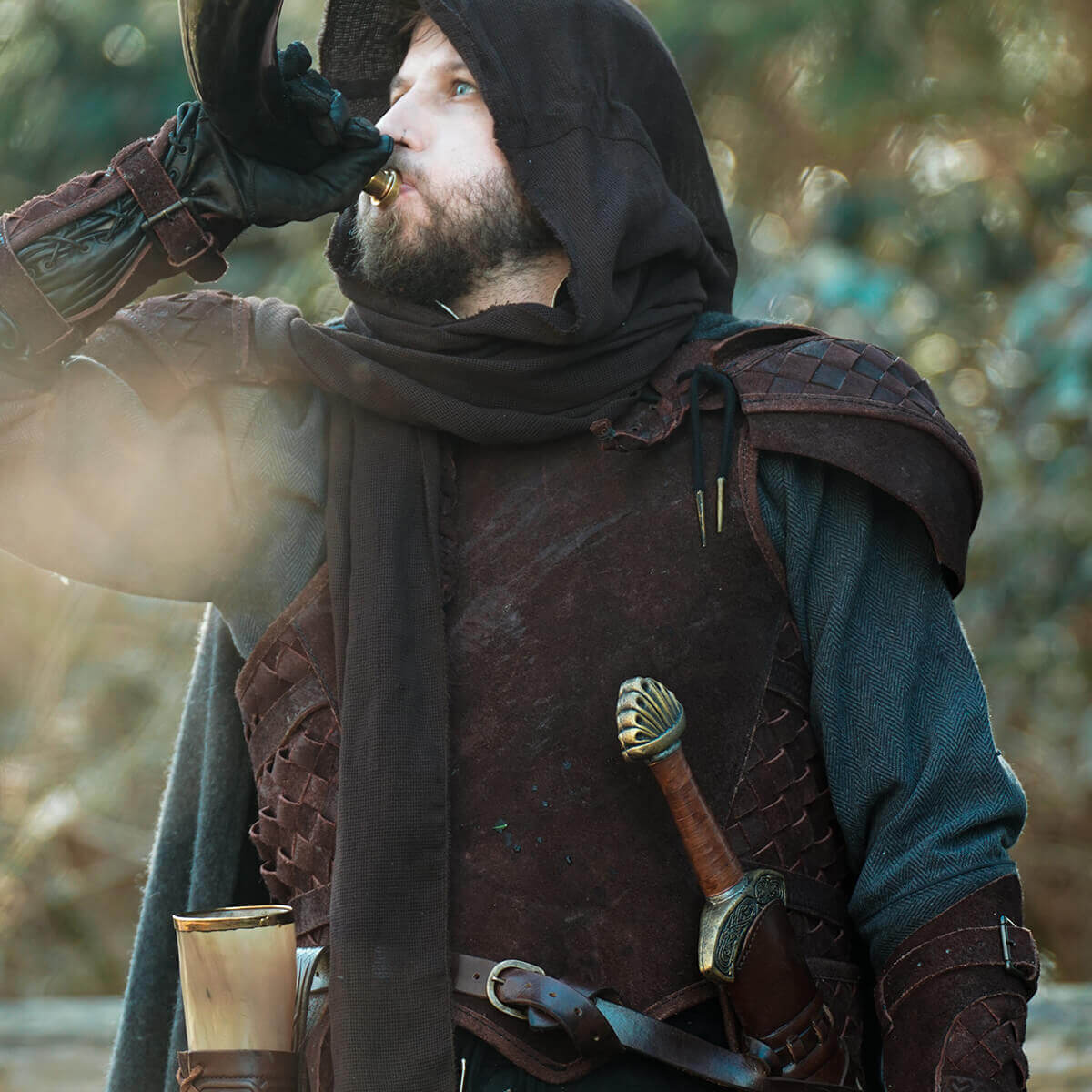 Man wearing weathered leather armor and hooded cloak, demonstrating weathering and aging leather armour techniques.