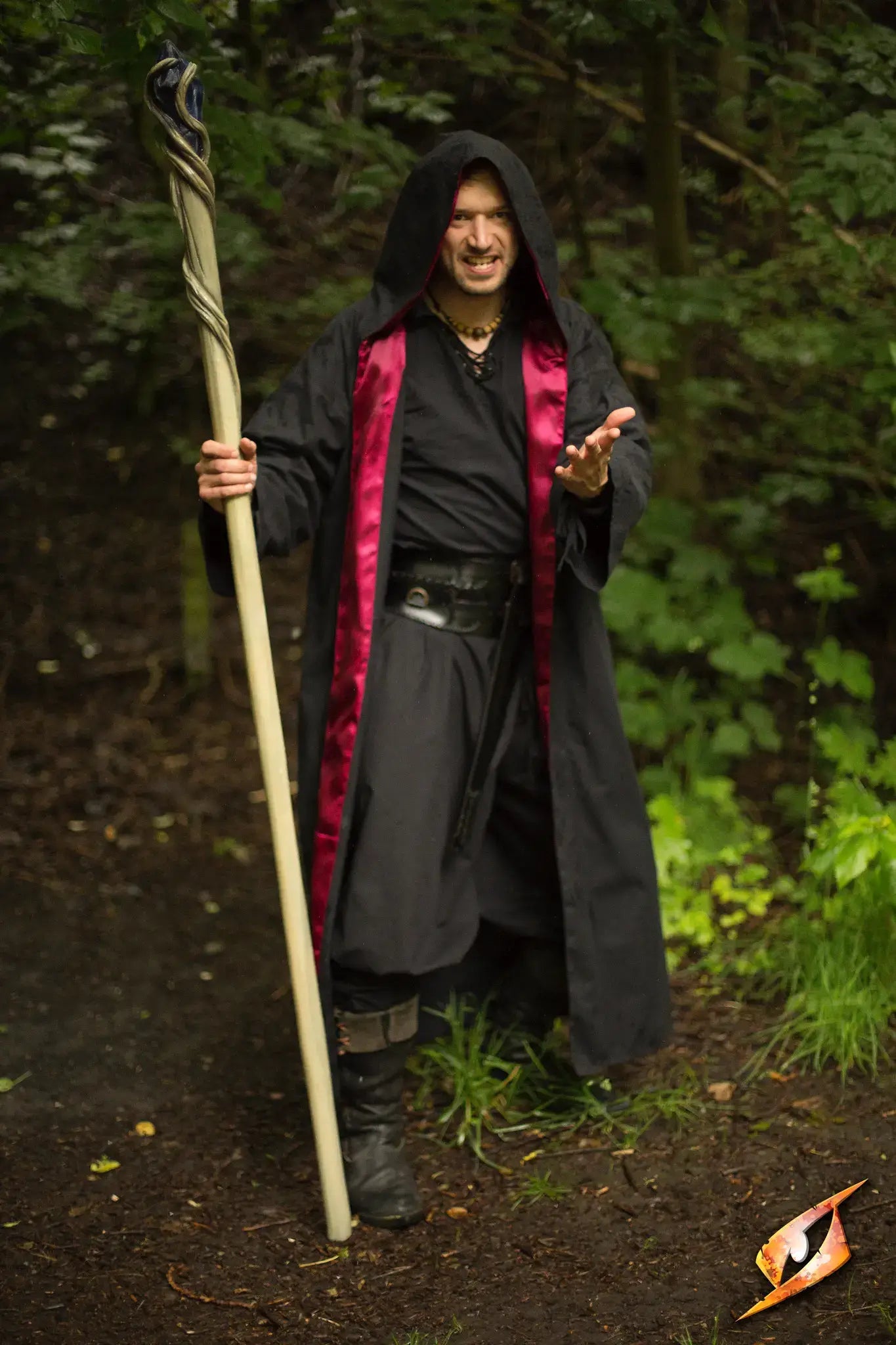 A wizard wearing a black robe with red accents holding a staff in a mystical forest setting, representing Robes.