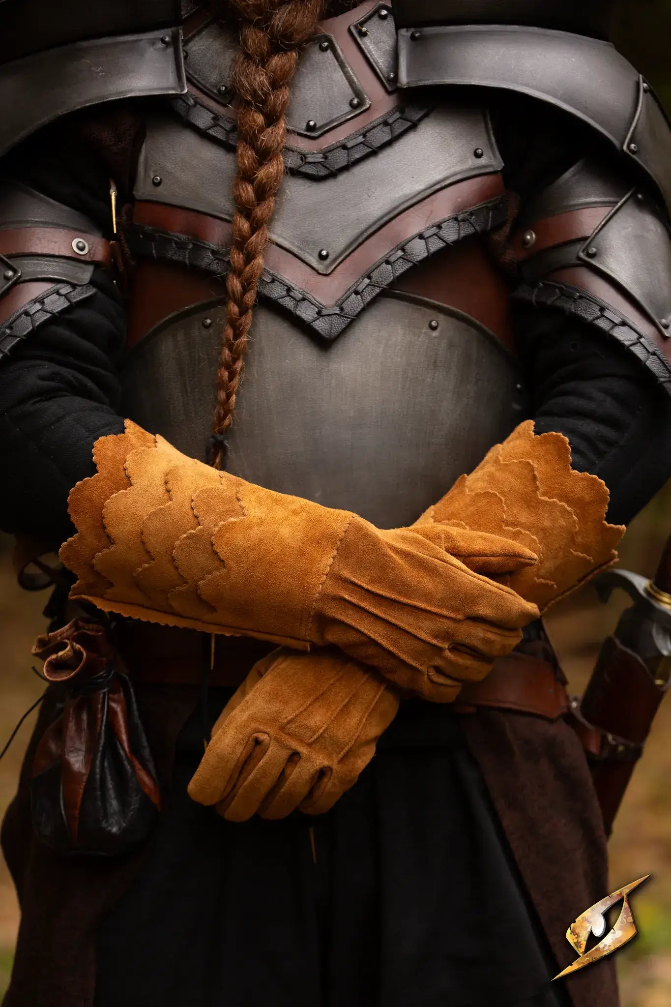 Two medieval-style gloves resting on arms crossed over a suit of armor, showcasing intricate design and craftsmanship. Gloves.