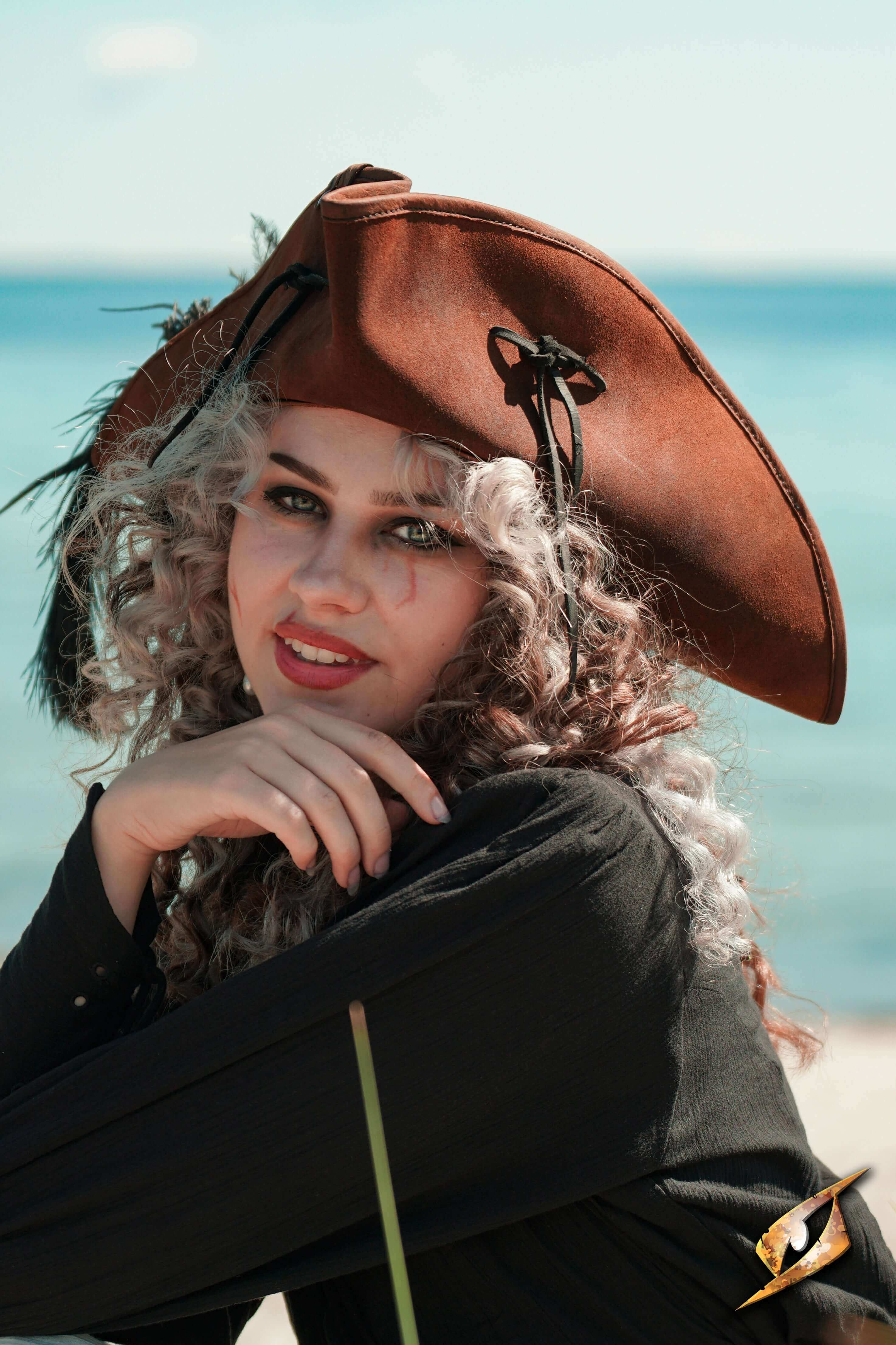 A model wearing a Simple Leather Pirate Tricorn Hat by the sea, showcasing its distinctive three-cornered design.