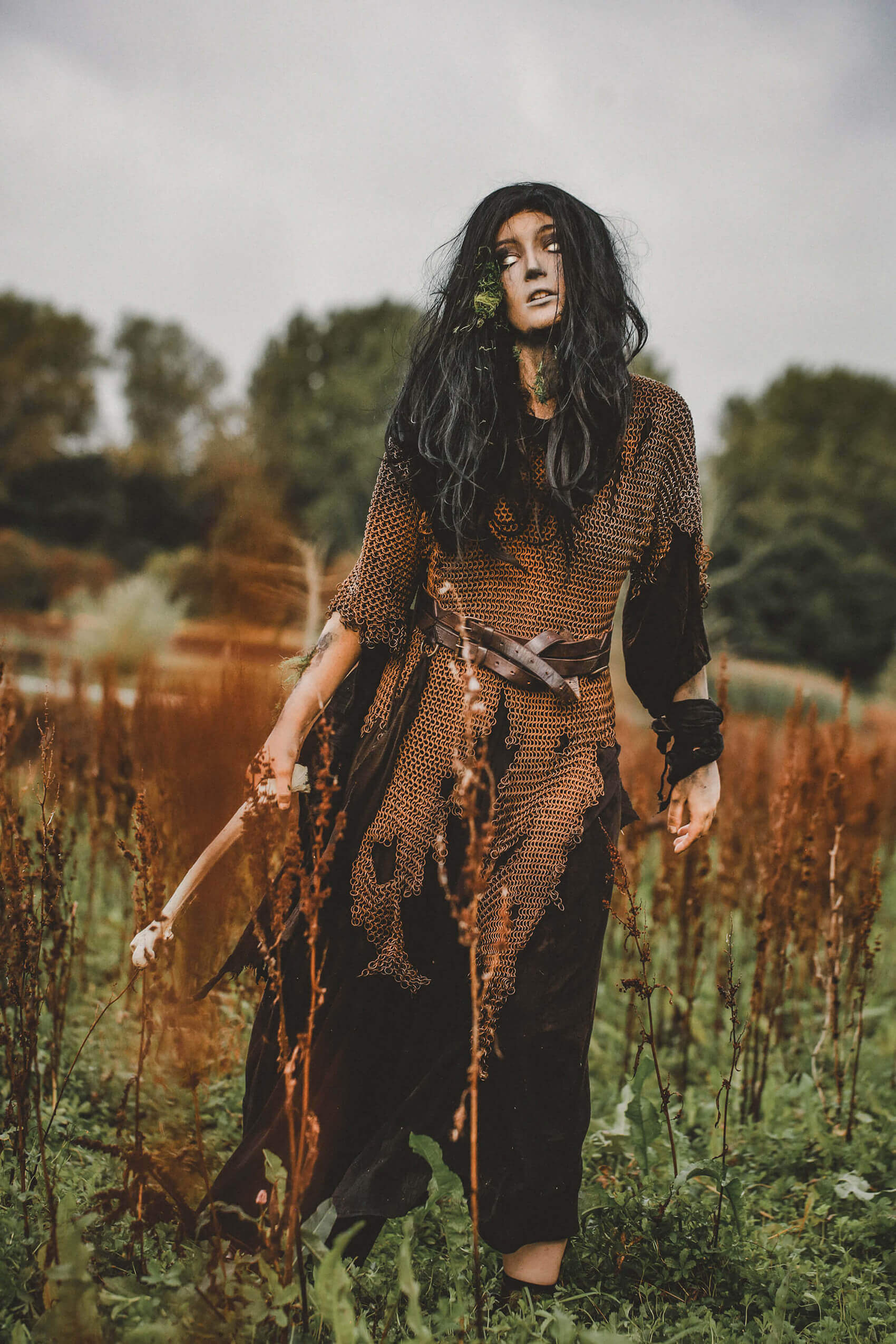 A spooky figure in a dark costume amidst tall autumn grass for a Halloween-themed image.