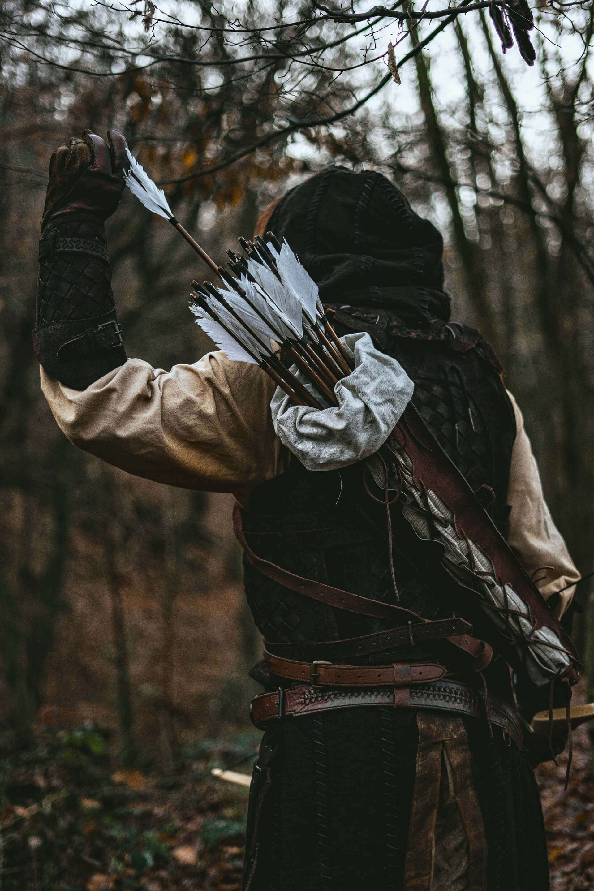 Ranged Weaponry: Archer drawing a bow with a quiver full of arrows in a forest setting.