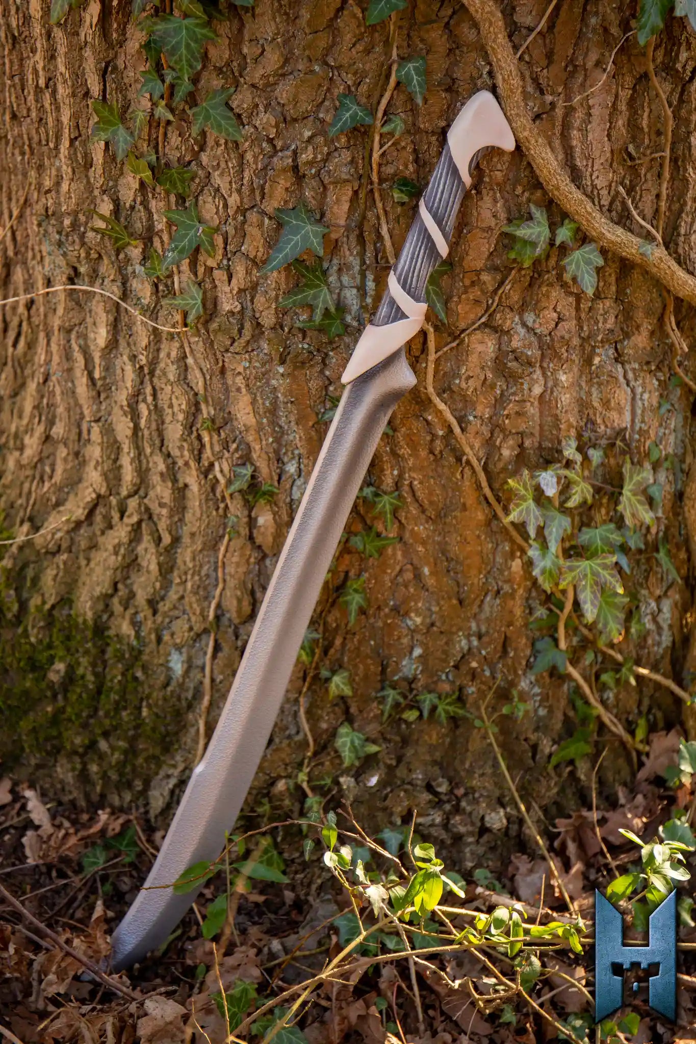 Elven Hunter Blade displayed against a tree with ivy, showcasing its elegant design and sharp edge.