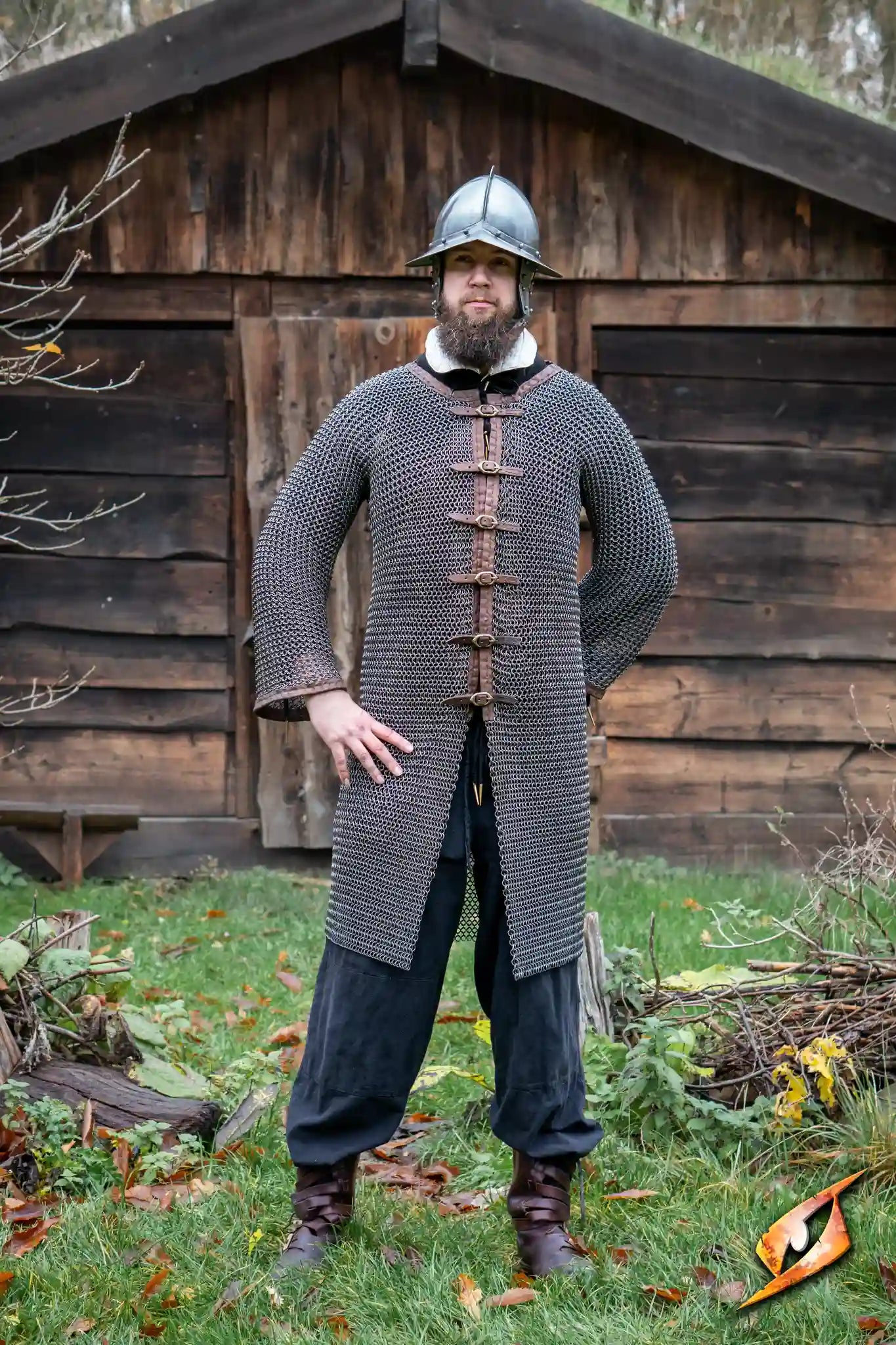 A person wearing the Captain Chainmail tunic in front of a rustic wooden building, showcasing its design and features.