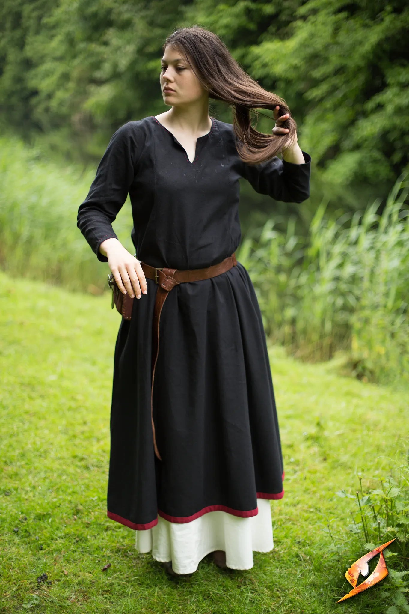 Woman wearing a Basic Dress with a long black skirt and a brown belt in a green outdoor setting.