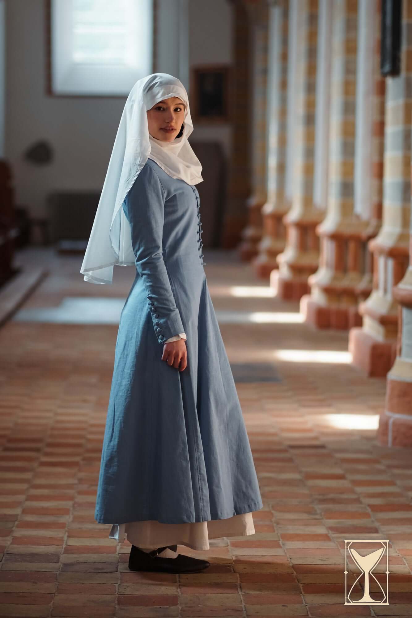 Cotehardie Marian dress model wearing a blue foundational high medieval dress with lacing details.