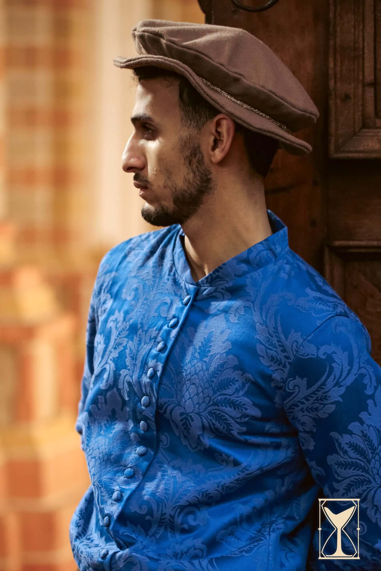 Flat Hat Edward worn by a model in a blue ornate shirt, showcasing Renaissance-style fashion.