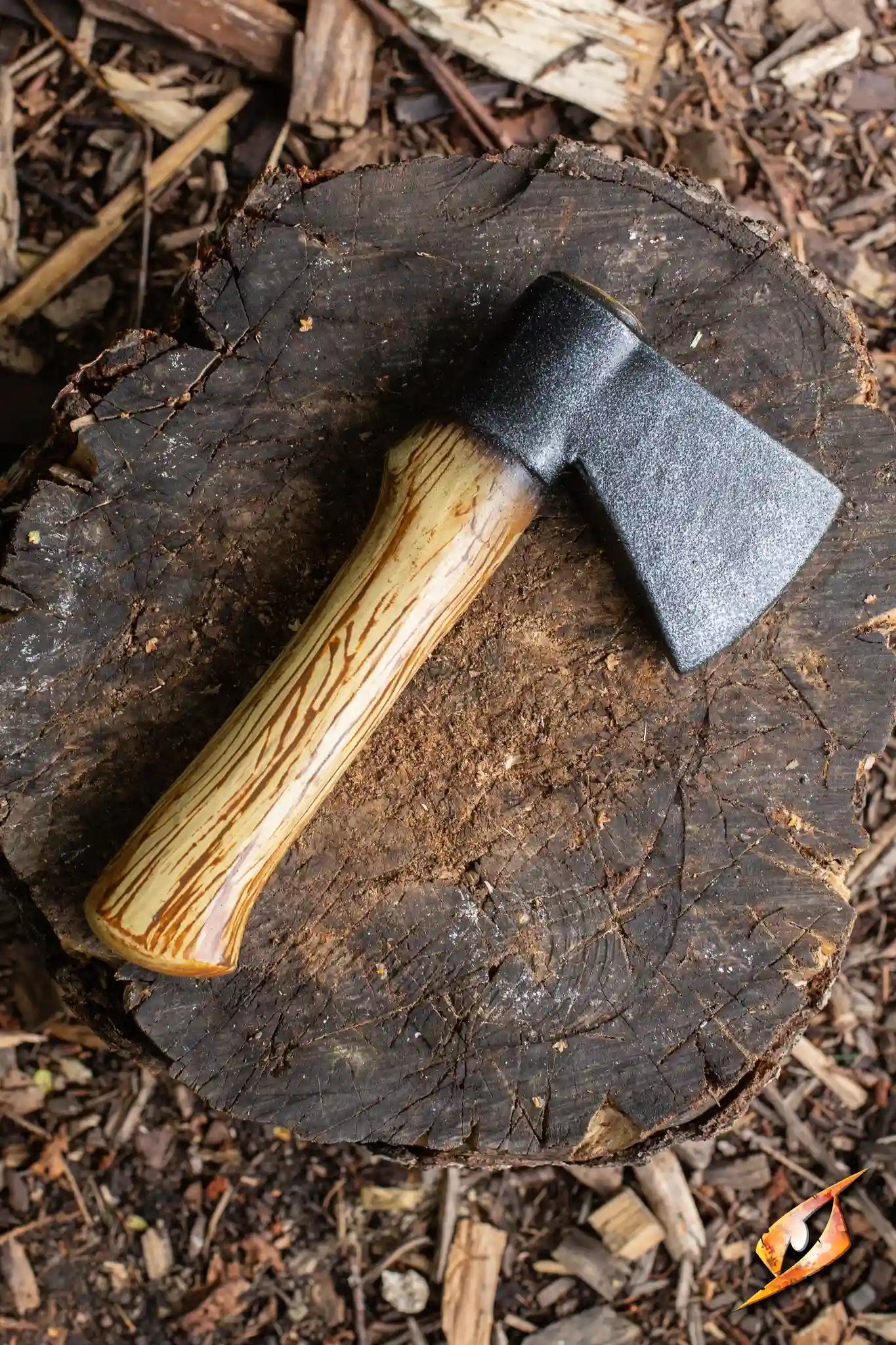 Woodsman Throwing Axe resting on a wooden log, showcasing its heavy one-edged blade and wooden handle.