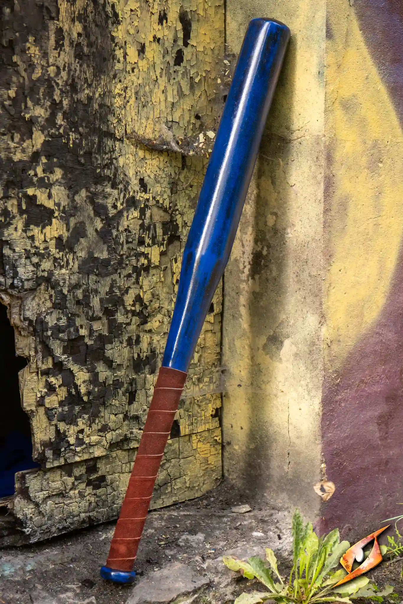 Blue baseball bat leaning against a weathered wall, perfect for defense against the undead.