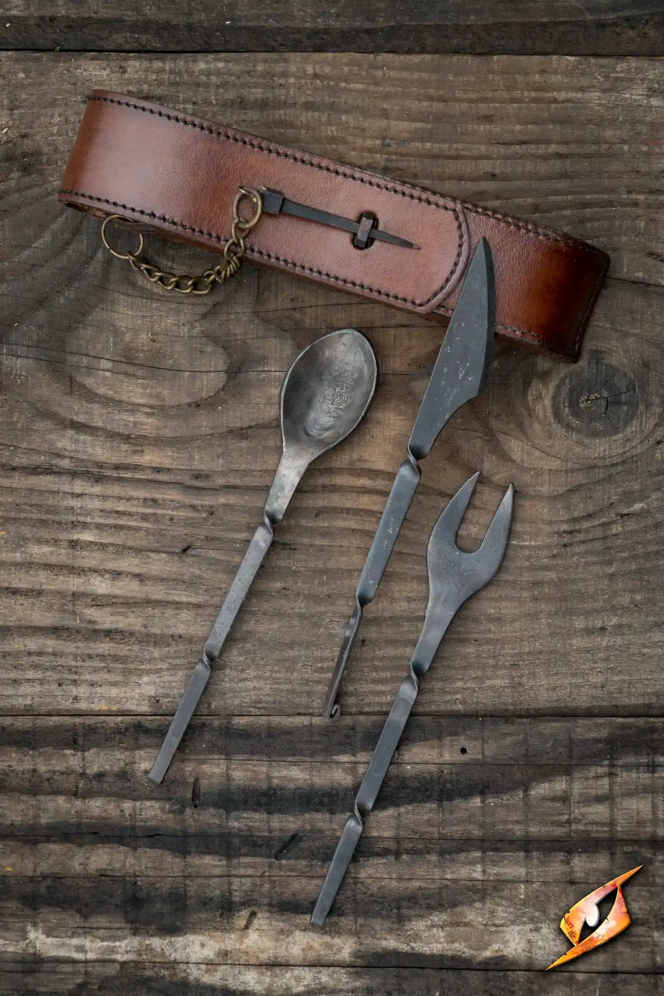 Set of metal cutlery with a leather belt on a wooden surface