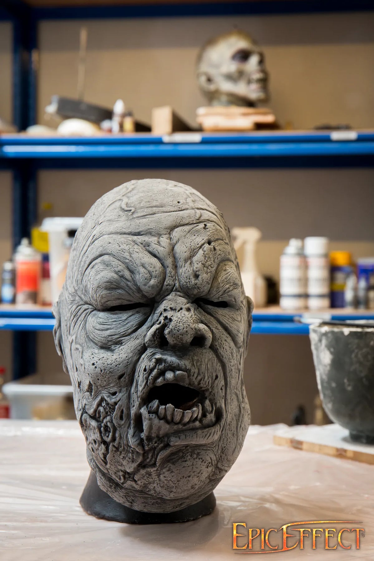 Big Rotten Zombie mask sculpture with textured skin and broken features in a workshop setting.