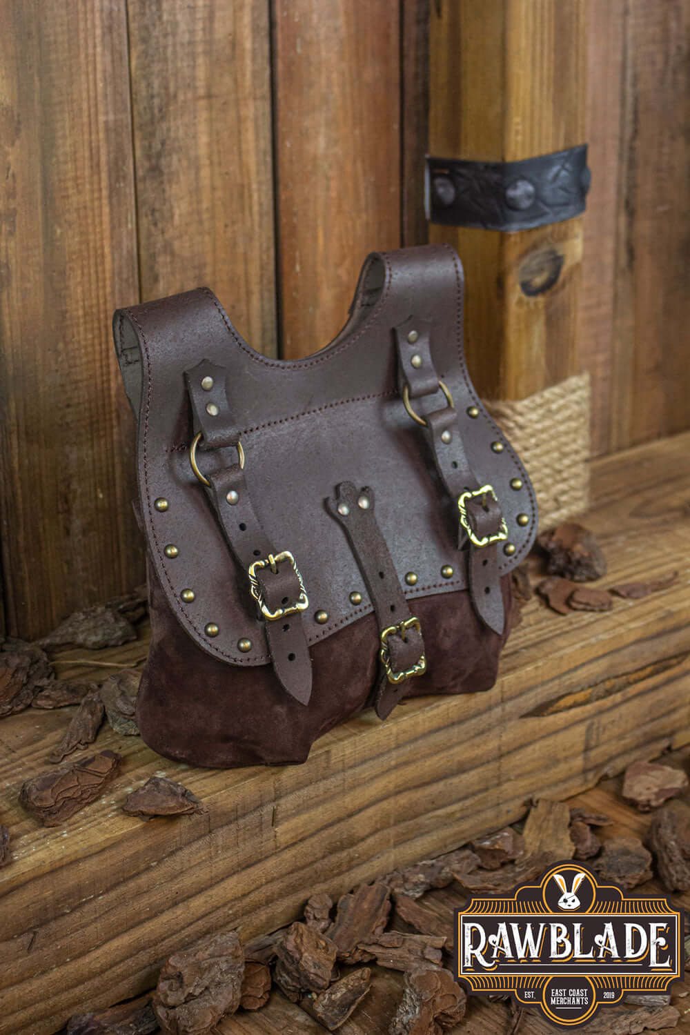 Agor Belt Bag in brown leather, featuring studs and adjustable straps, showcased on wooden background.