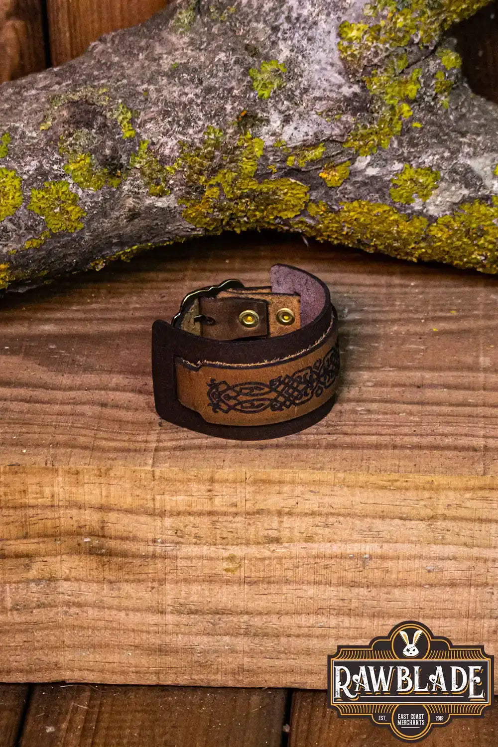 Beleriand Leather Bracelet on wooden table with engraved black filigree and golden buckle